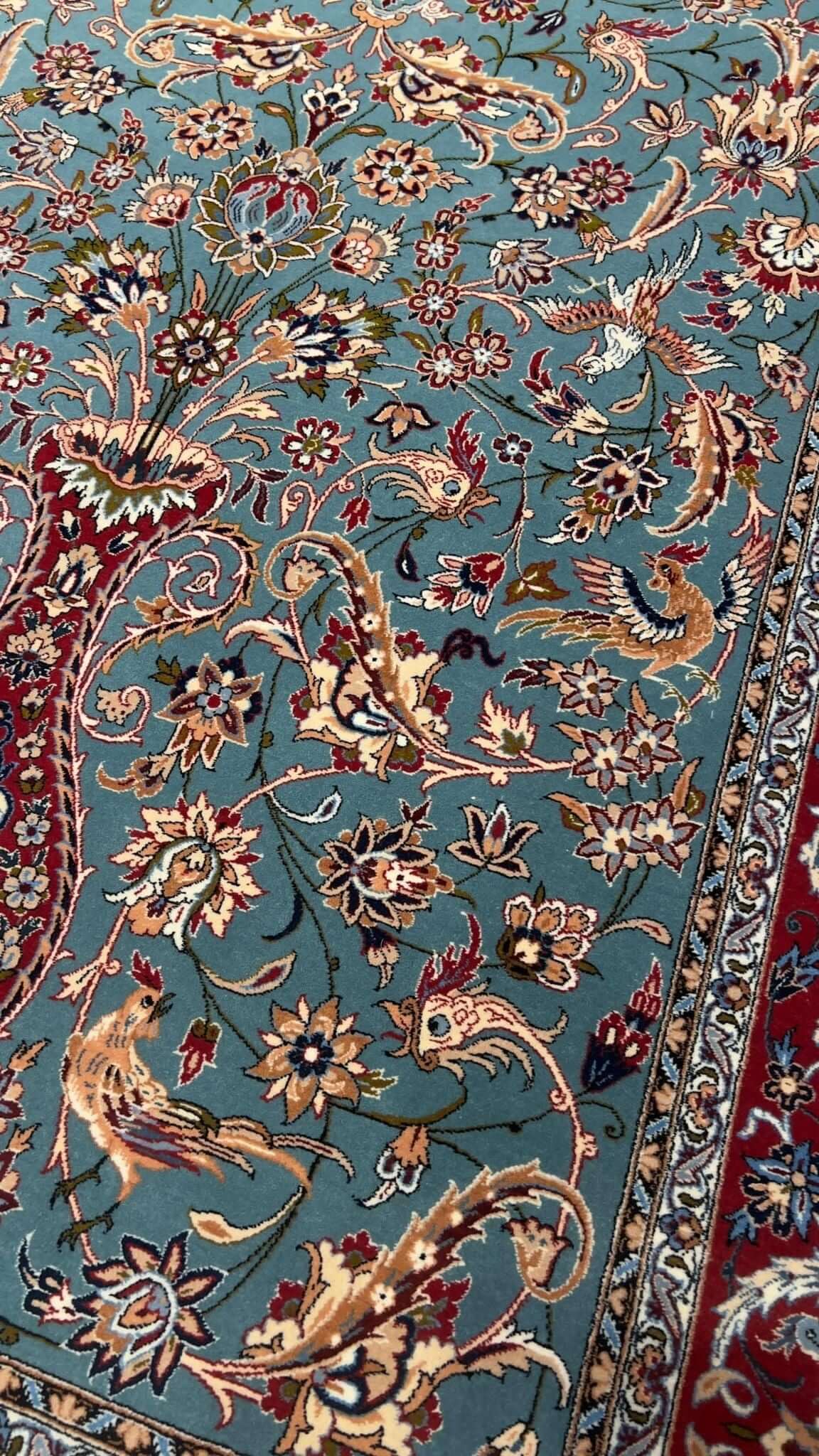"Close-up view of the intricate floral patterns on the light blue Persian rug by Master Zojajie, highlighting the hand-knotted silk and wool craftsmanship."